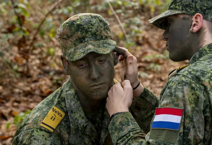 VeVa medewerker Grondoptreden - studenten brengen CFP camouflagegezichtsverf aan in de bossen