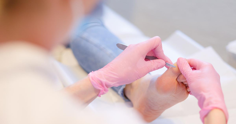 Pedicure behandelt een voet van een client.