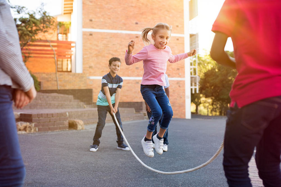 Kinderen zijn aan het touwtje springen op een schoolplein.
