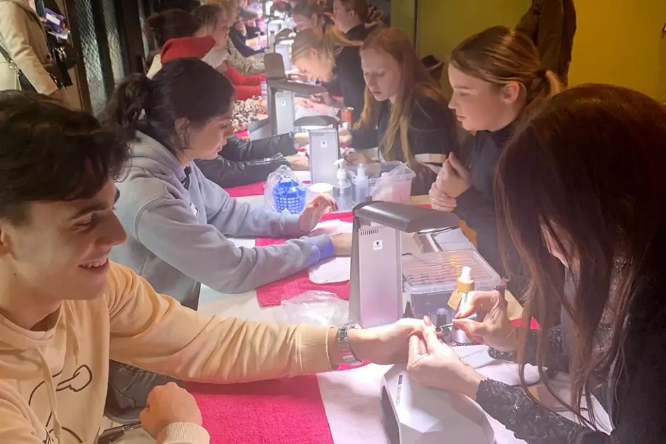 Summa collega's laten hun nagels lakken aan een lange tafel