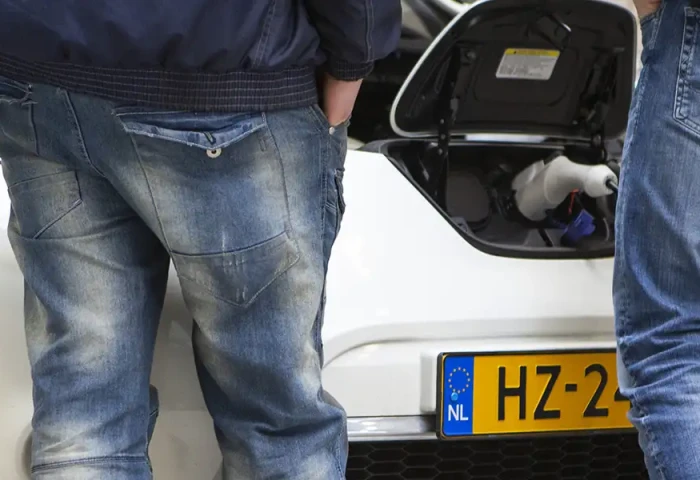 Drie mannen staan bij een electrische auto waarvan de kap open is.