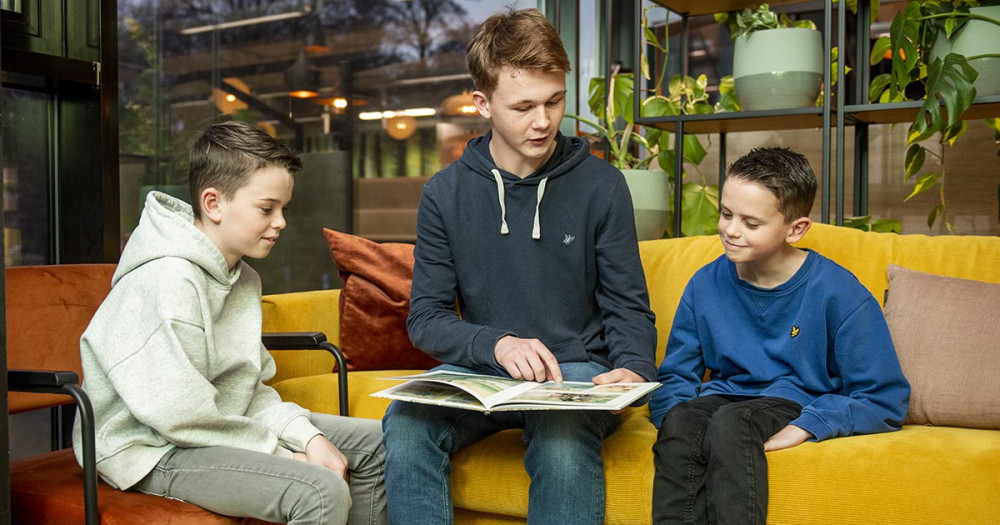 Onderwijsassistent aan in gesprek met twee leerlingen.