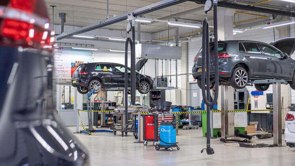 Je ziet auto's op een brug staan in een werkplaats.