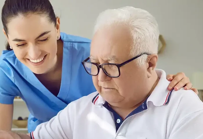 Een verzorgende kijkt met de arm om de schouder van een senior toe hoe deze een puzzel maakt.