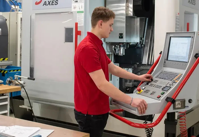 Een jongeman bedient een freesmachine.