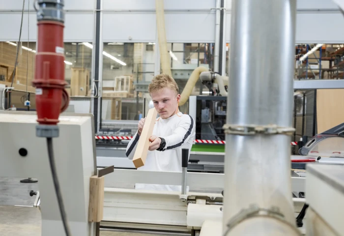 Houtbewerker kijkt langs een balk om te controleren of die recht is.