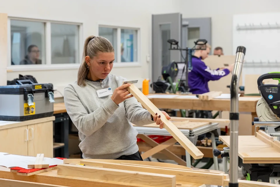 Demi Houbraken in de werkplaats. Ze controleert of een onderdeel van haar meubel met een winkelhaak.