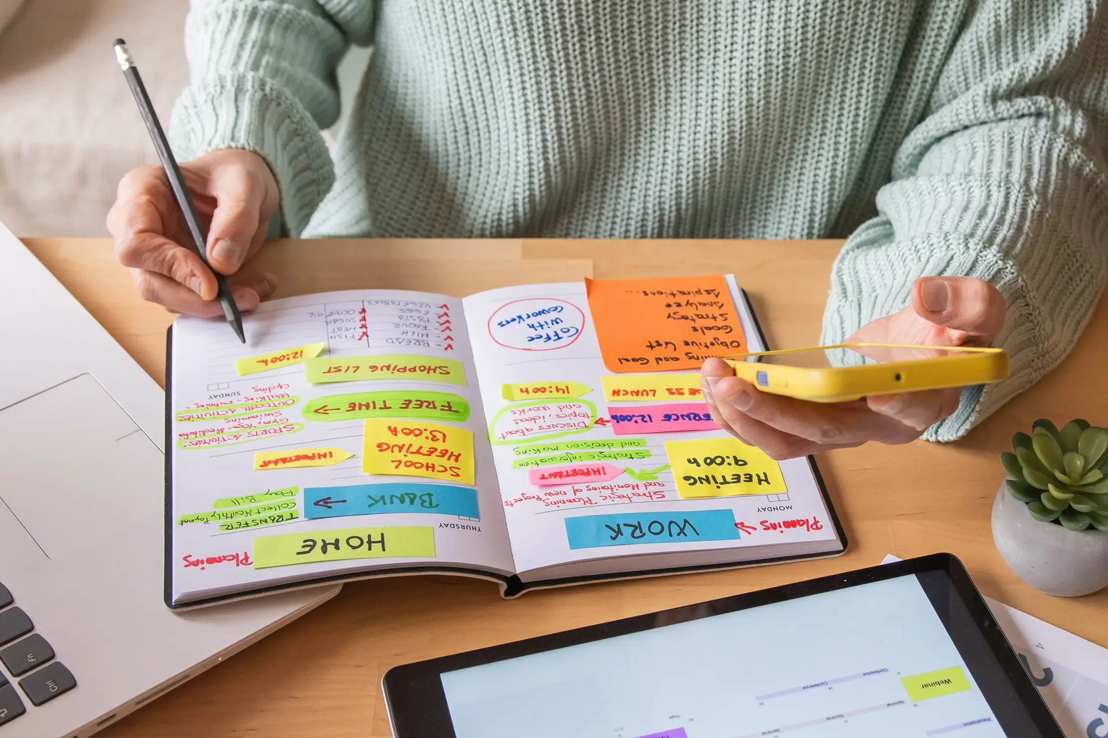 Woman writing in a notebook and holding her phone