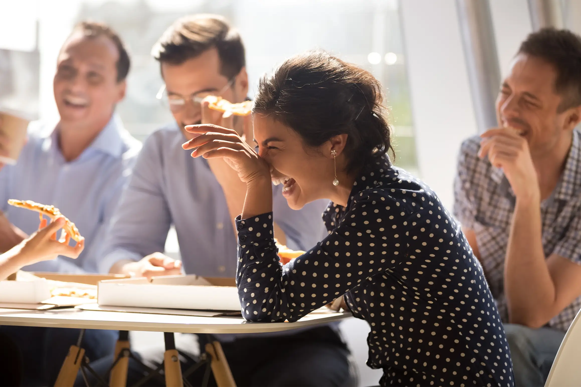 A group of people are sitting at a table, laughing loudly.