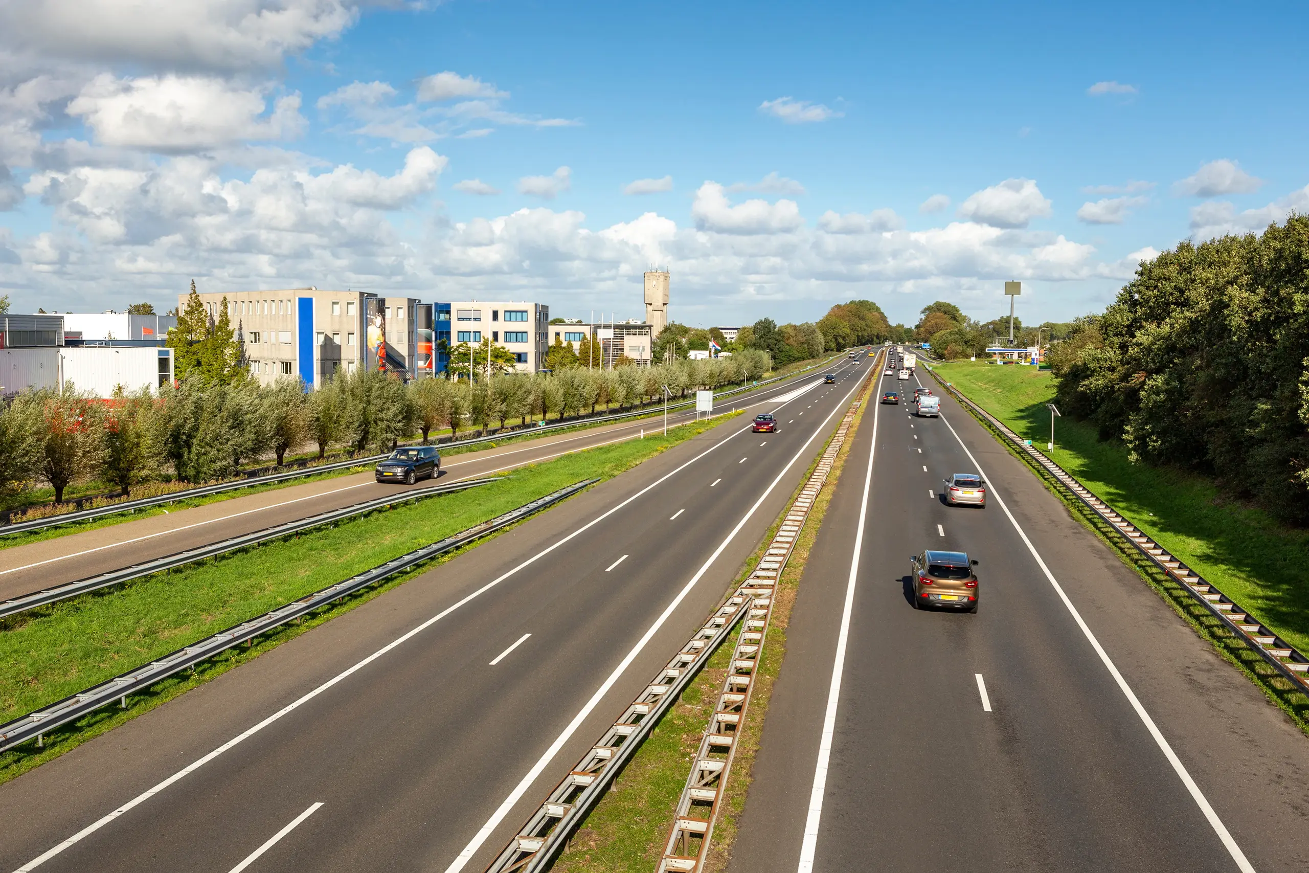 The highway seen from an overpass. There's an office park on the left.