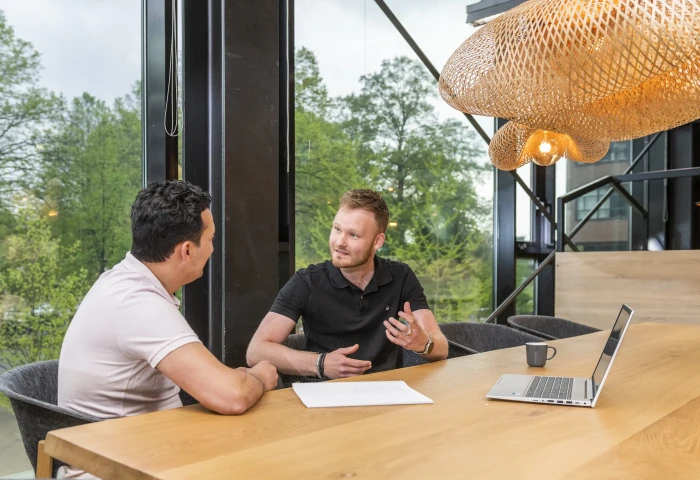 Student en begeleider overleggen aan tafel